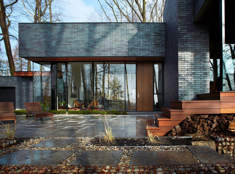 The home’s low, elongated form and earthy materials, like brick and wood, echo the tones of the escarpment and surrounding forest.
