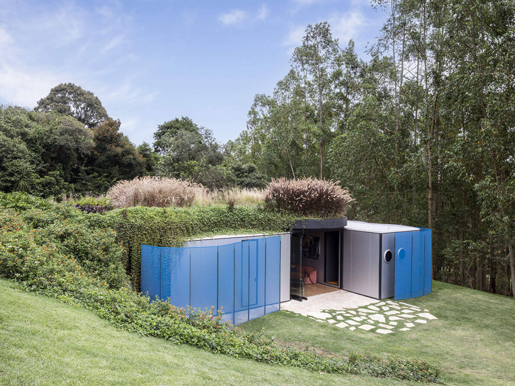 Wrapped in sky-blue steel and softened with curved walls, this prefabricated home hides its modular roots. Rodrigo Ohtake’s clever use of industrial materials brings surprising warmth and elegance.