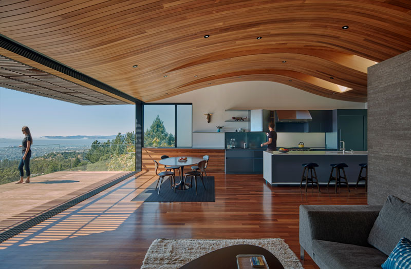 Curved wood ceilings echo the hillside landscape while extending toward the balcony views.