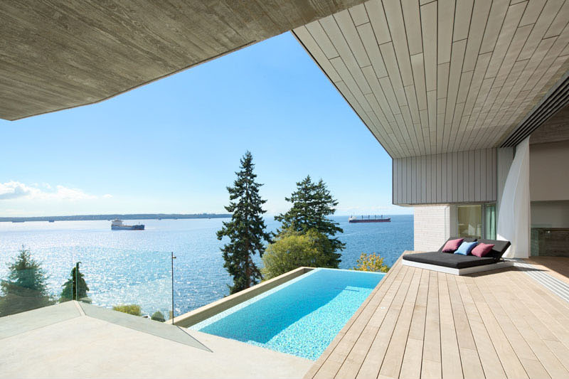 A sleek swimming pool and garden terrace sit below a concrete platform in this split-level oceanfront house.