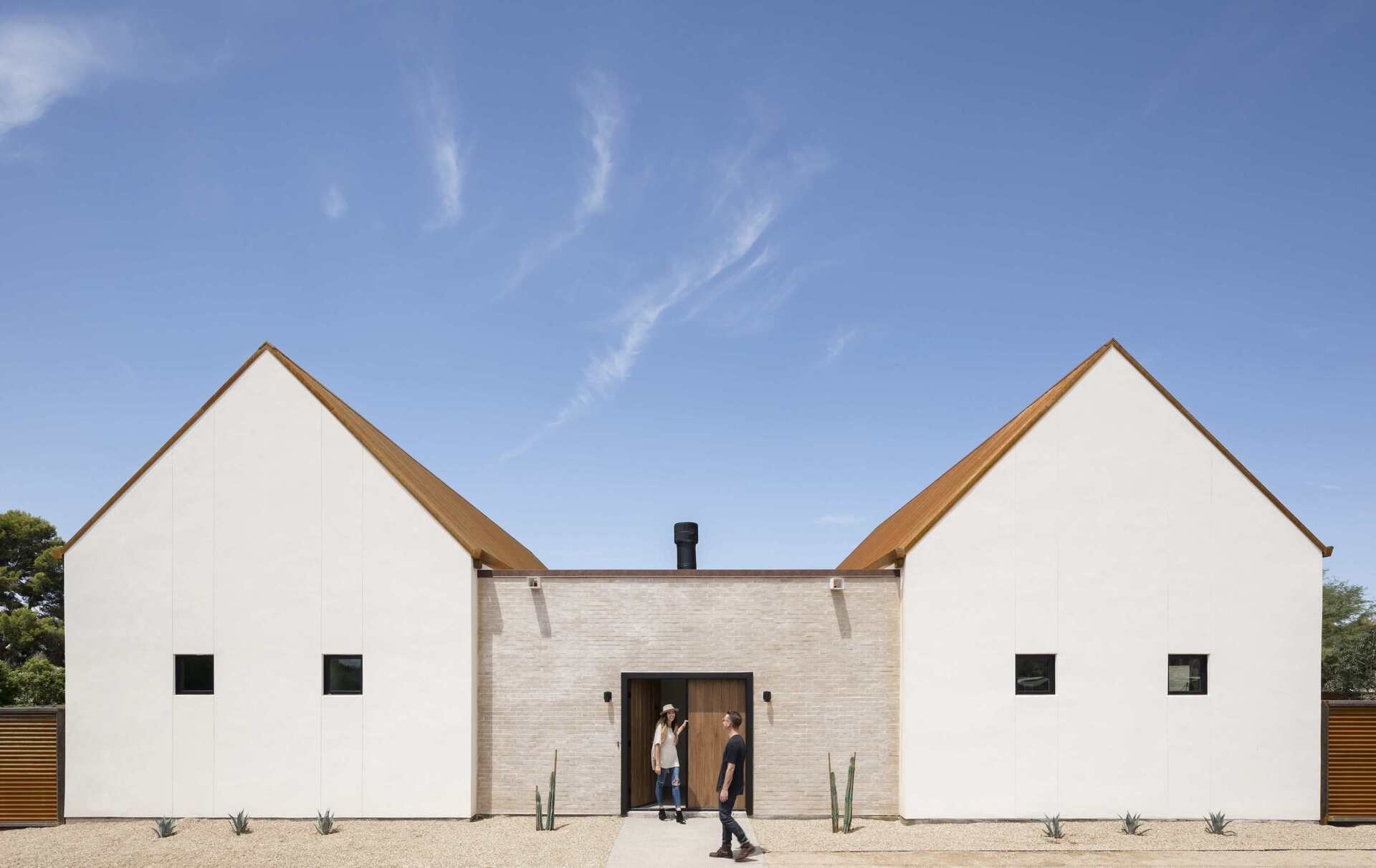 A modern desert home in Phoenix blends mission-inspired forms, white brick walls, and a rusted metal roof to capture Arizona’s light and history.