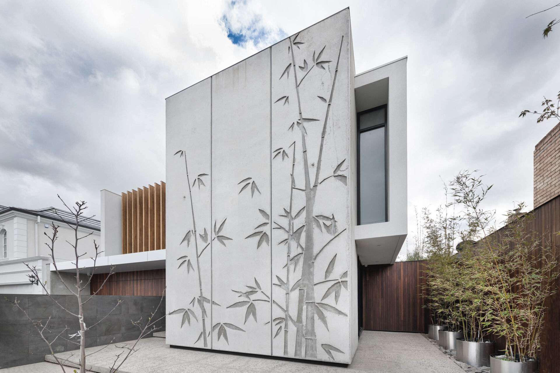 Tilt-up concrete panels with bamboo reliefs give this home a sculptural edge. The combination of raw concrete and natural texture strikes a balance between industrial and organic design.