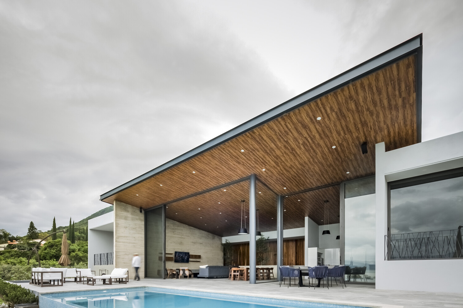 Sliding glass walls open to a pool, firepit, and shaded lounge, turning every day into lakeside living.