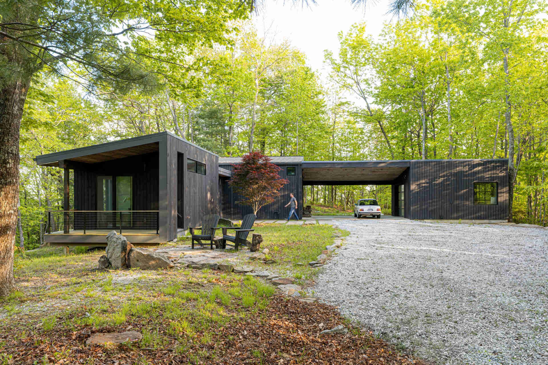 A modern mountain cabin in Sapphire, NC, featuring two pavilions forming a courtyard, black-stained pine exterior, and a minimalist Japanese-Scandinavian design.