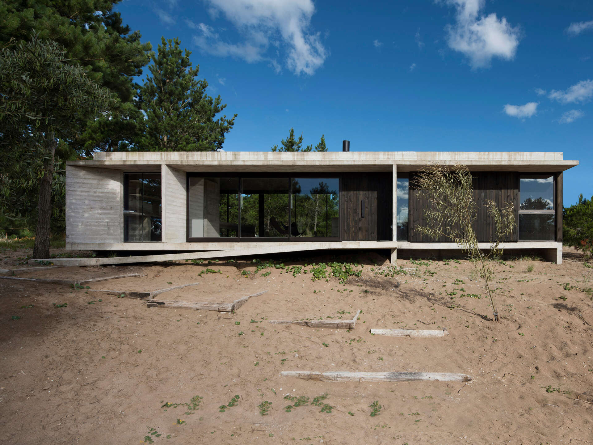 A modern concrete and wood home in Costa Esmeralda designed to sit gently on a forested site while keeping its natural terrain intact.