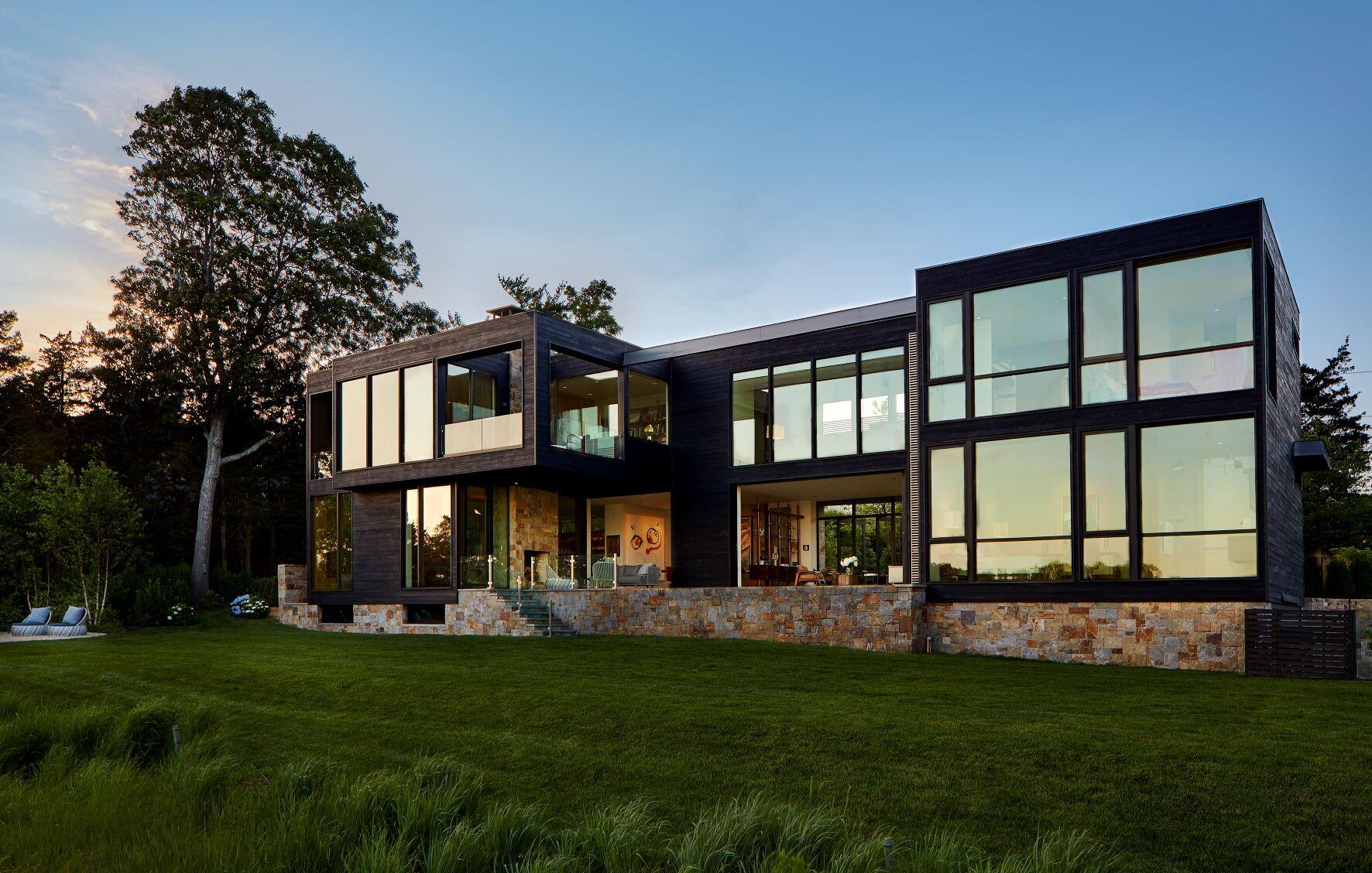A modern home with a stone base and a swimming pool