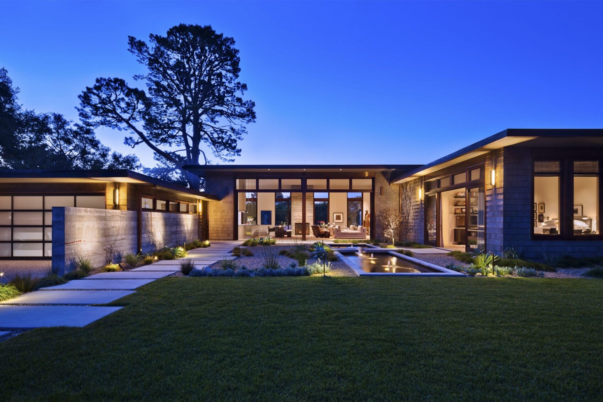 A serene Montecito courtyard with water, stone, and greenery creates a tranquil welcome to this modern home.