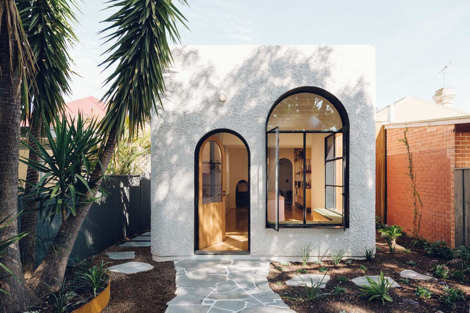 A white facade with dramatic black lined window reveals adds depth, shade, and visual impact to this art decor inspired home extension.