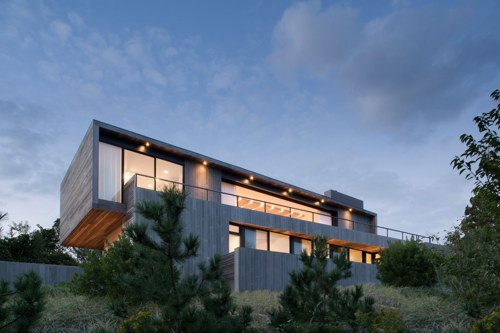 Weathered mahogany decking spans roofs, walls, floors, and ceilings, paired with locally sourced bluestone walls that anchor this Montauk beach house into the land.