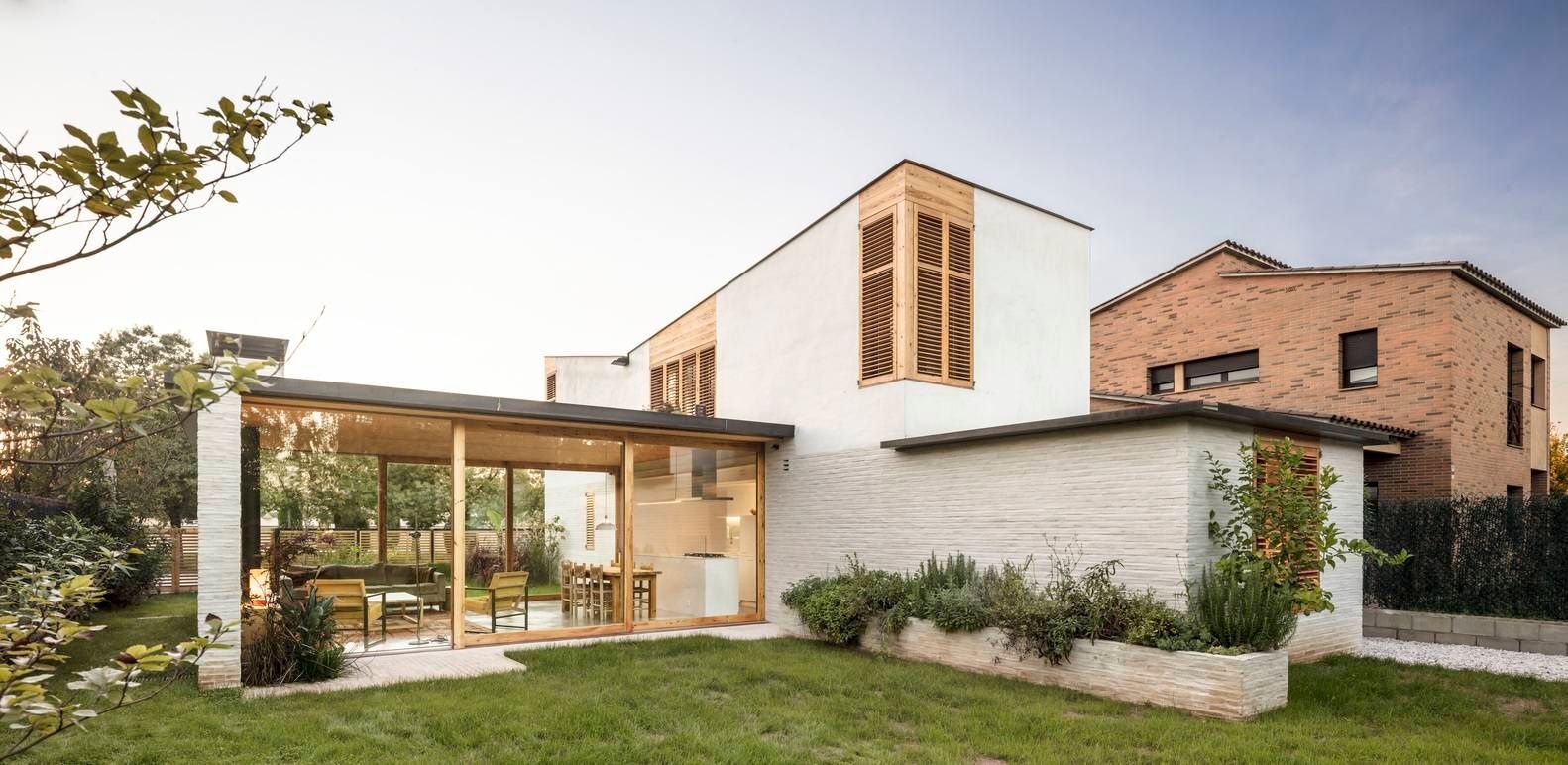 This Spanish family home is shaped by two contrasting volumes, a slender vertical block for privacy and a glass-lined entertaining area that opens fully to the garden.
