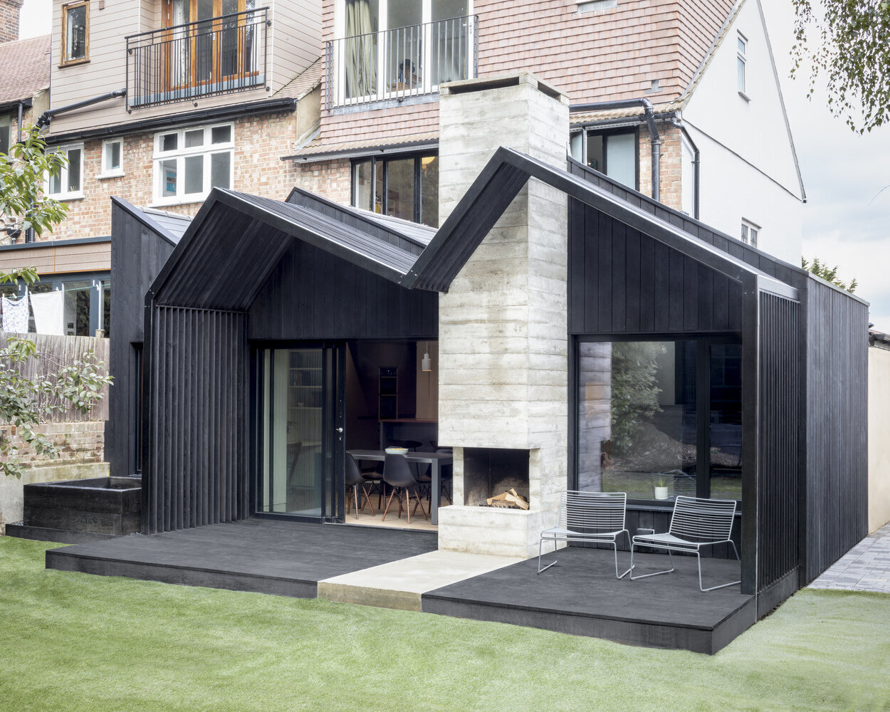 The bold dark extension with a ribbon of concrete highlights the sculptural fireplace, creating a striking profile at the back of this South London terrace.
