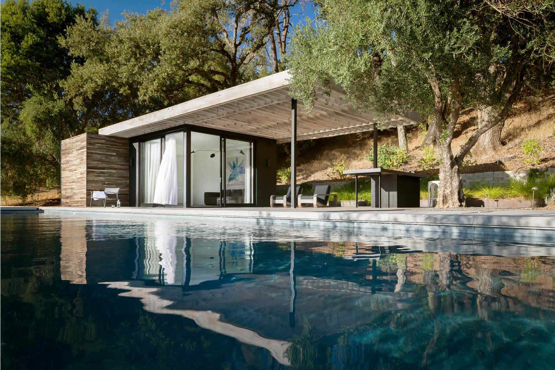 Reclaimed vineyard grape stakes wrap the exterior of this pool house, creating privacy while filtering light and views across the landscape.