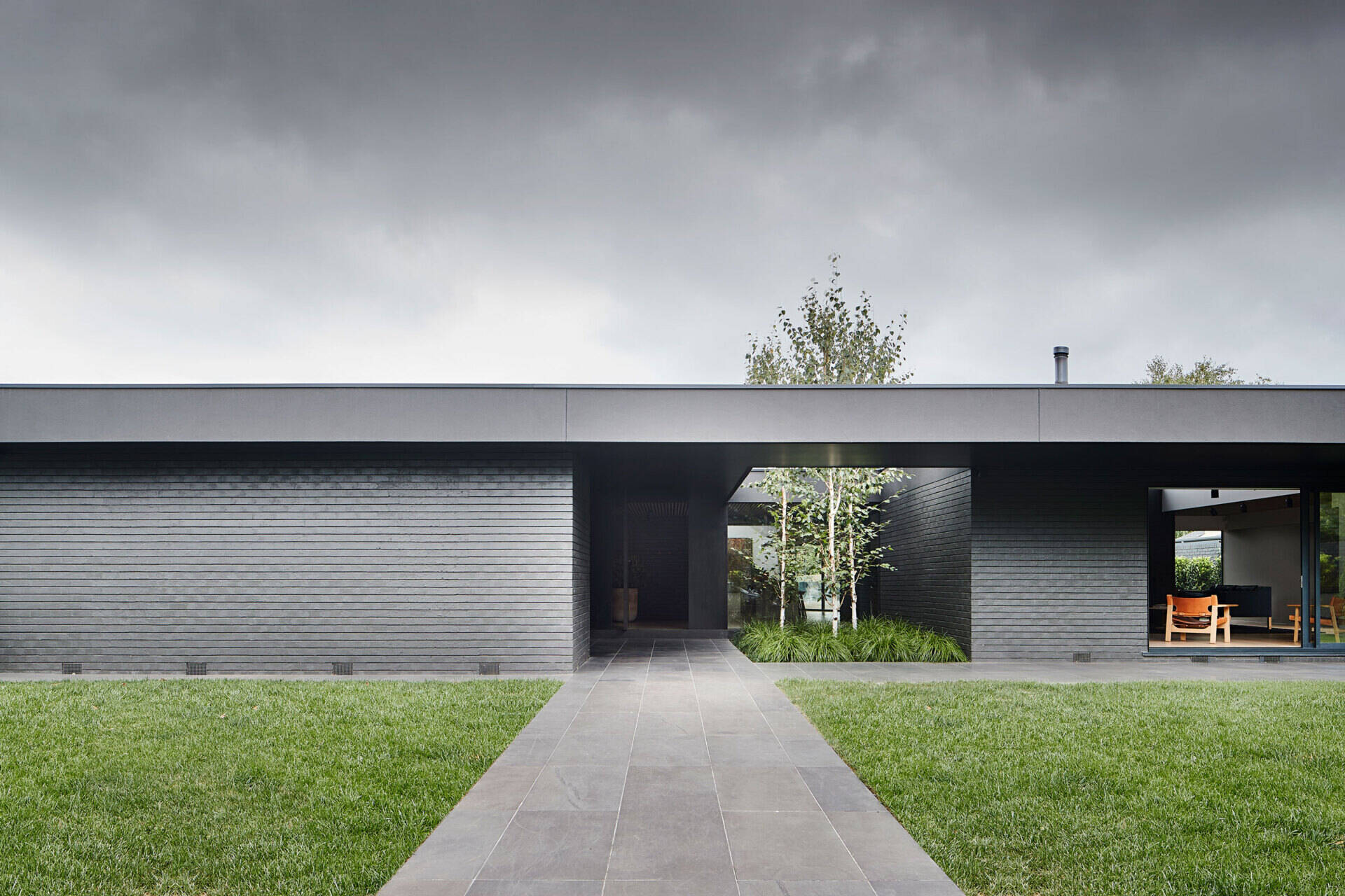 An oversized eave and soft landscaping define the entry to this Australian home, creating privacy, light, and a strong sense of arrival.