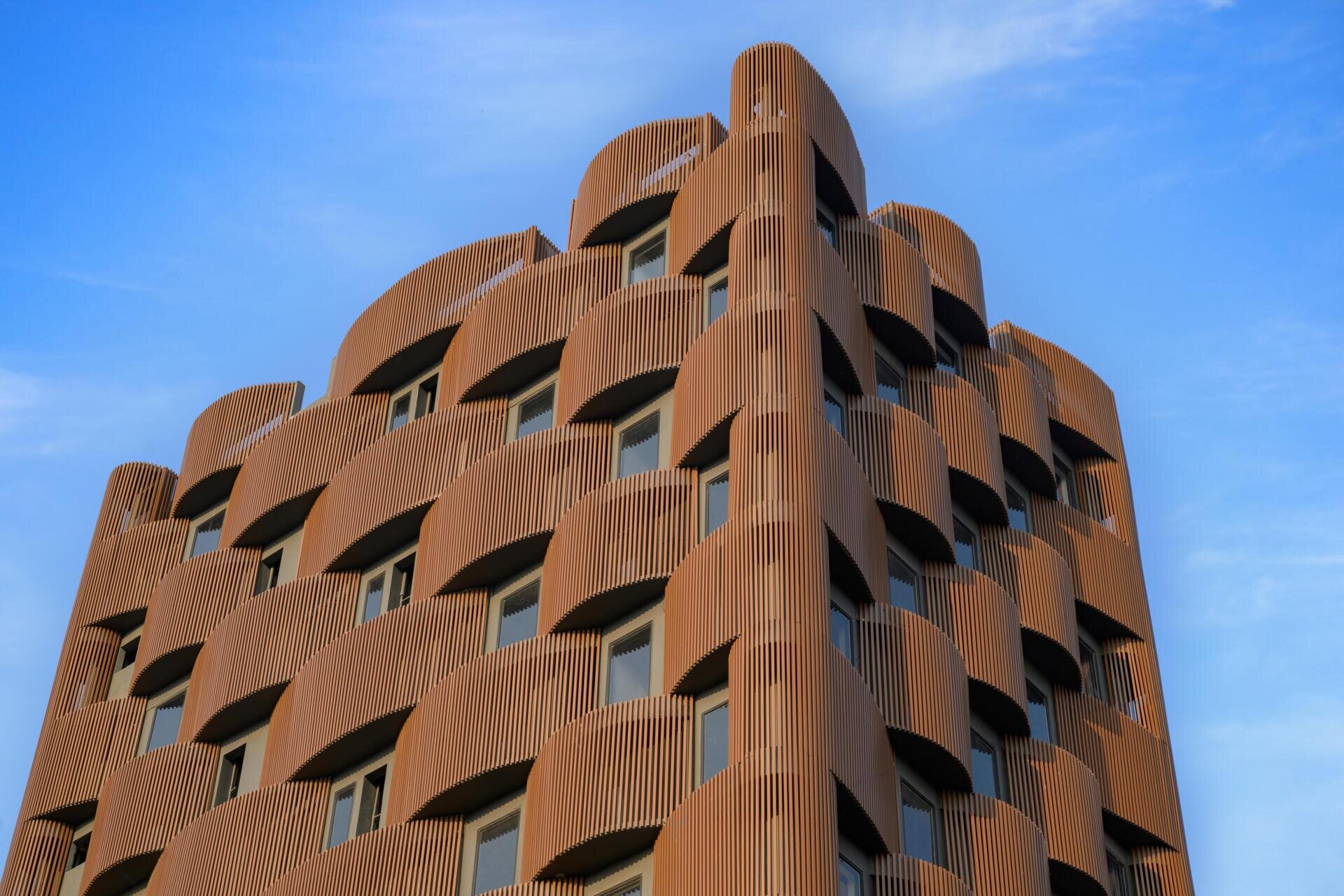 This 14-level office in Nagpur replaces the typical glass facade with layered decks, aluminum louvers, and greenery designed for 48°C summers. A climate-smart approach to modern workplace design.