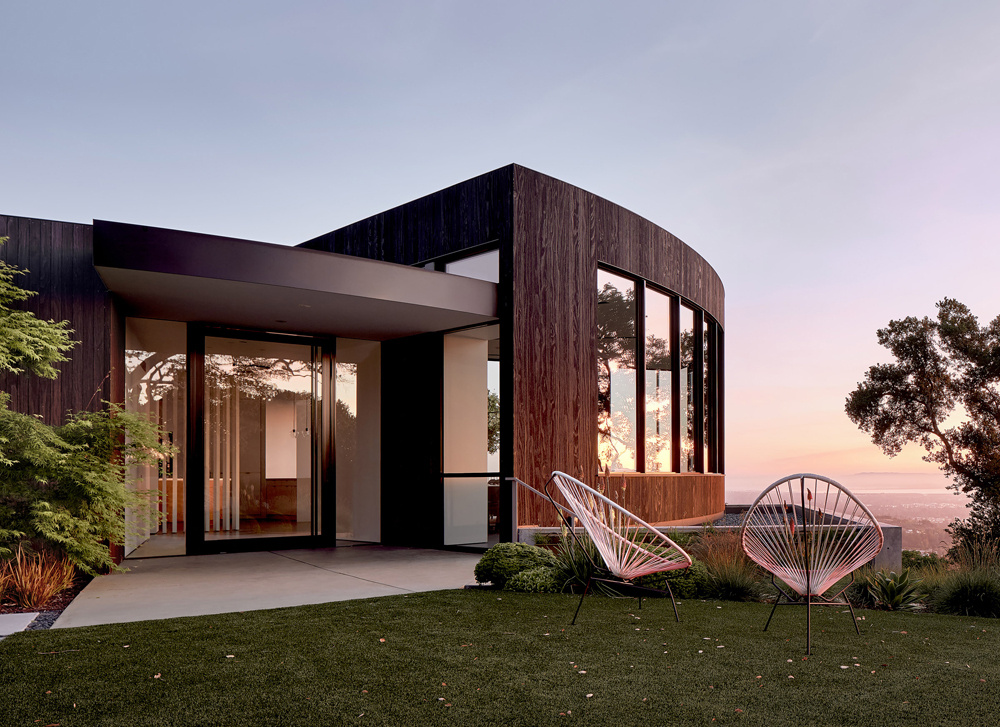 Charred wood siding, seamless concrete floors, and curved white walls modernize the Round House while respecting its original 1960s geometry.