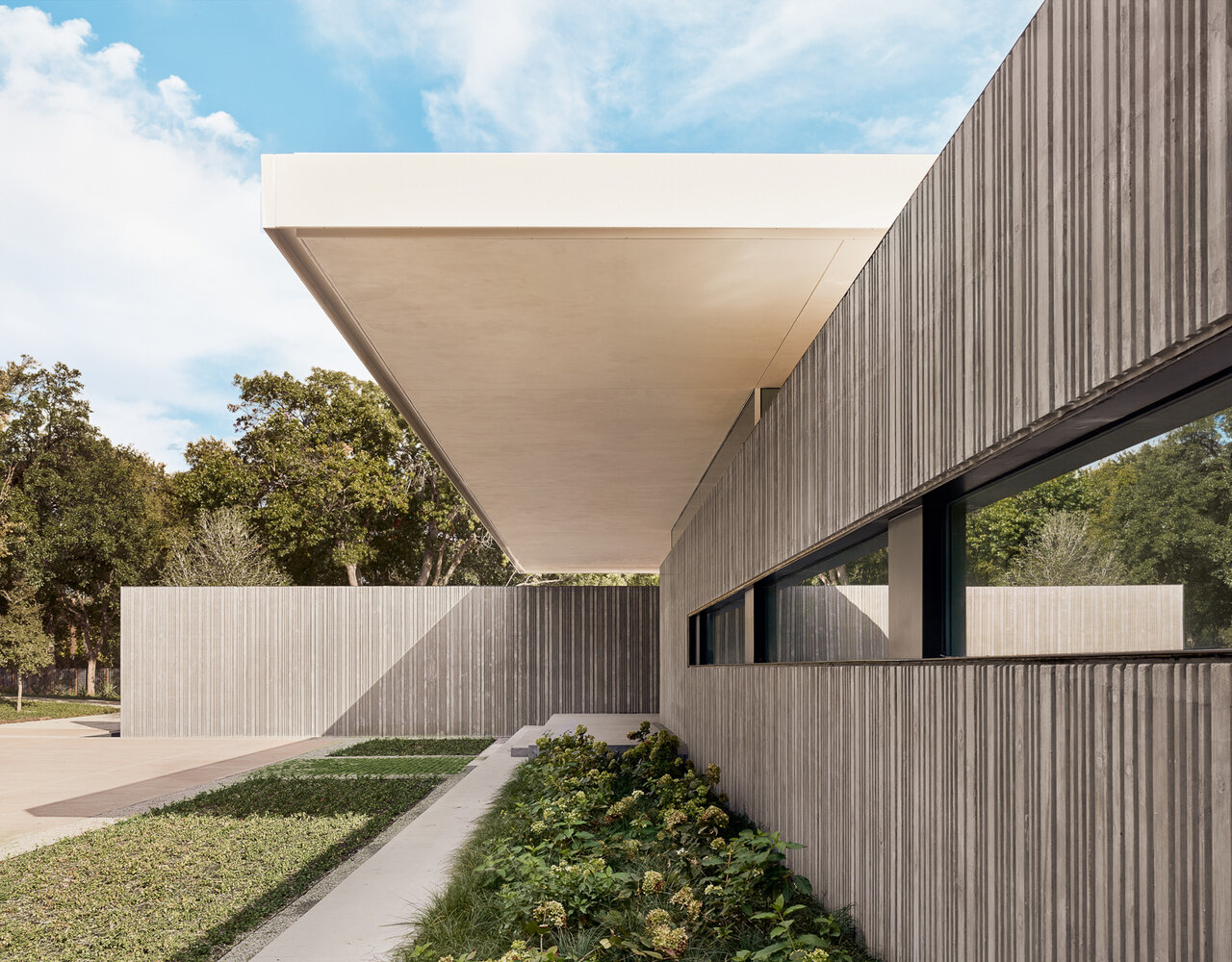 Custom-fabricated formwork gives these concrete walls their distinctive corrugated texture, creating depth, pattern, and ever-changing shadows throughout the day.