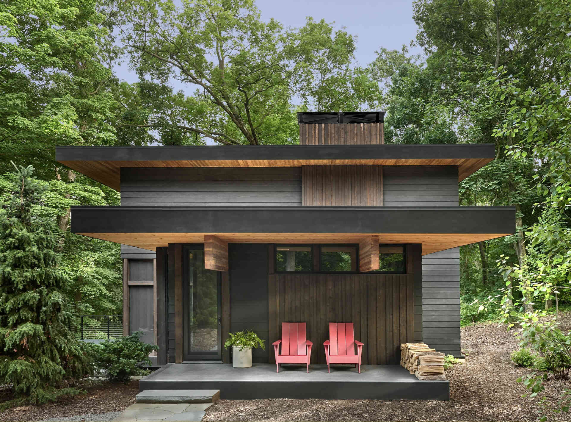 A striking black house tucked along a Michigan state park, designed to blend quietly into the trees while framing expansive valley views.