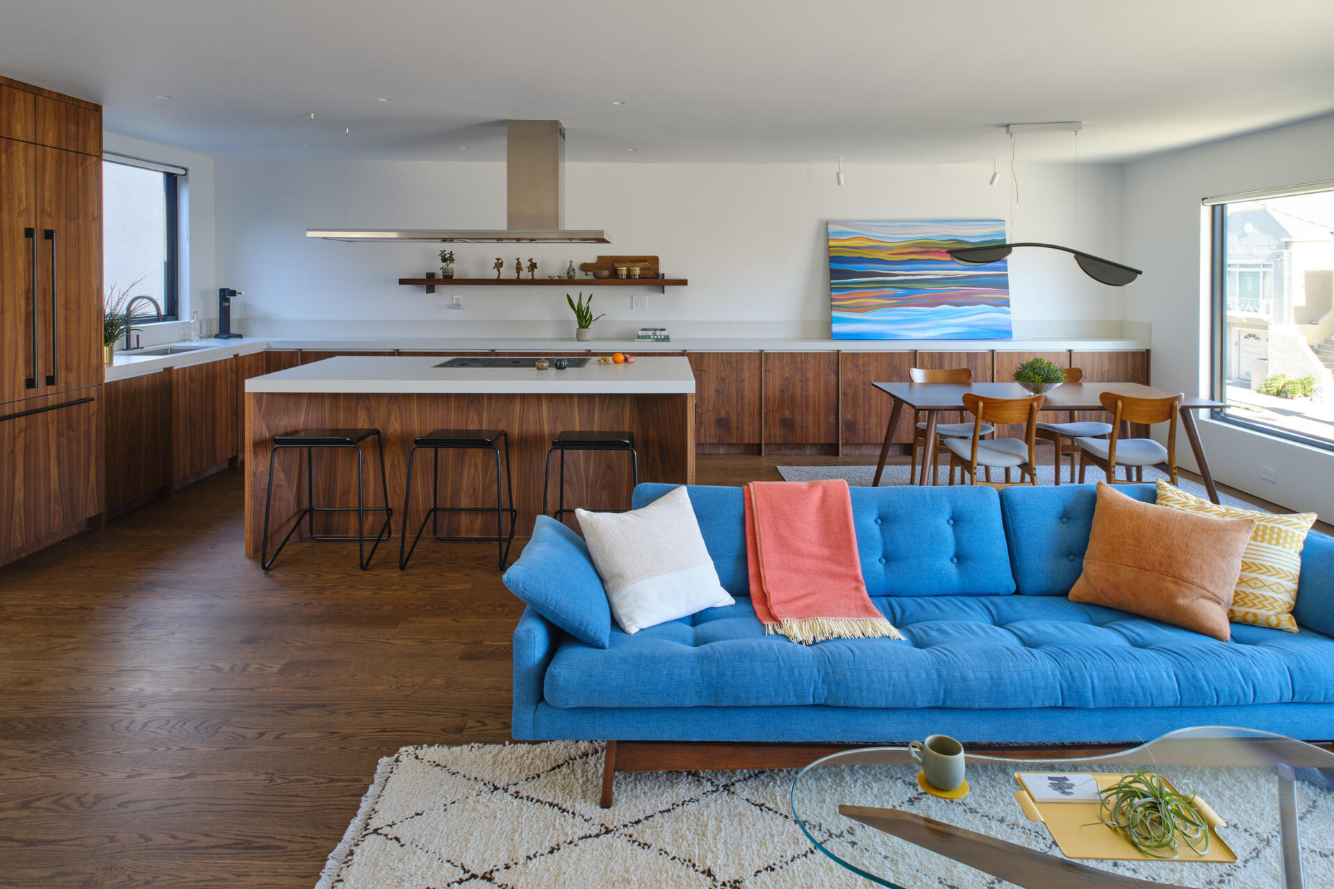 Previously, living spaces were segmented, cutting off visual connections and natural light. The layout felt constrained by its compartmentalized plan. Now, the living and dining areas unfold within the open upper level. Refinished original oak floors in a deeper tone ground the space, complemented by walnut millwork that adds warmth without overwhelming the volume.