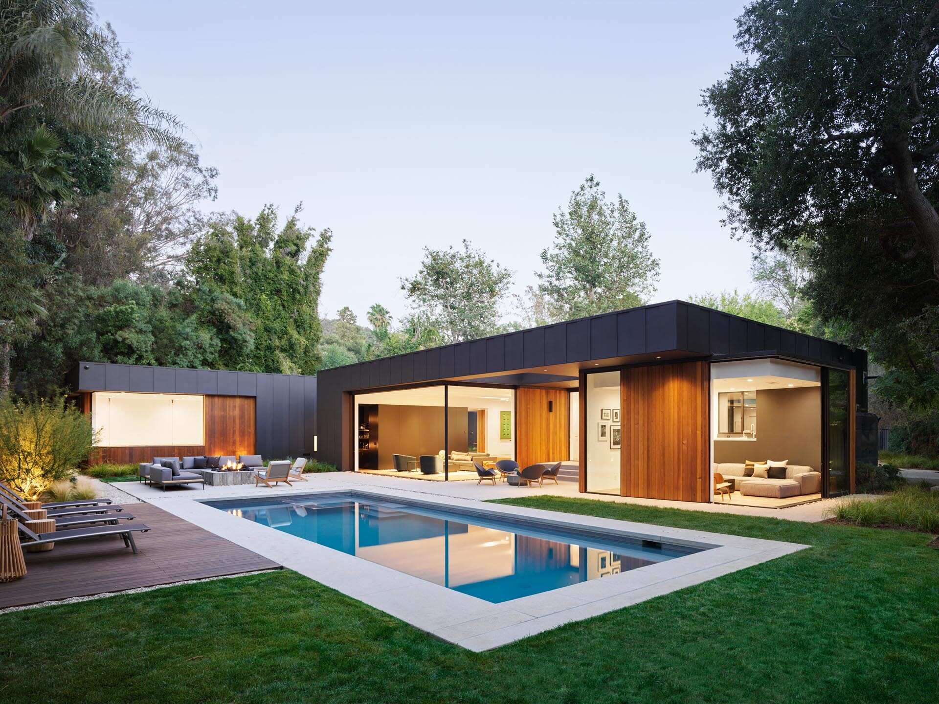 A 40-foot swimming pool and outdoor lounge with fire pit extend a cedar-clad Los Angeles home into its landscaped backyard.