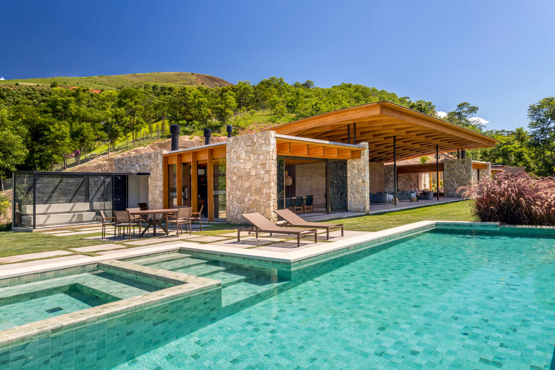 A sweeping wooden grid roof curves across the social spaces, supported by only eight slim metal pillars. It feels light and airy, framing views and glowing warmly at night.